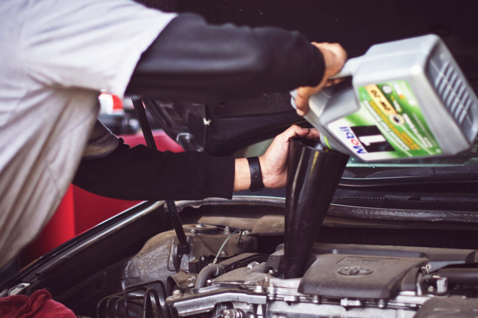 Mechanic pouring oil into automobile engine